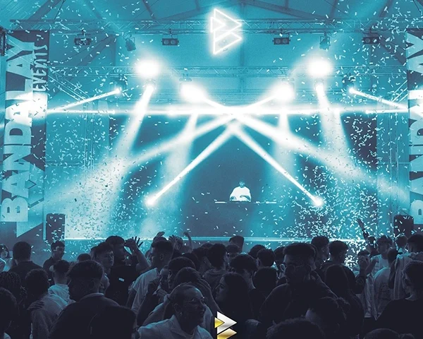 escenario iluminado con dj y gente bailando